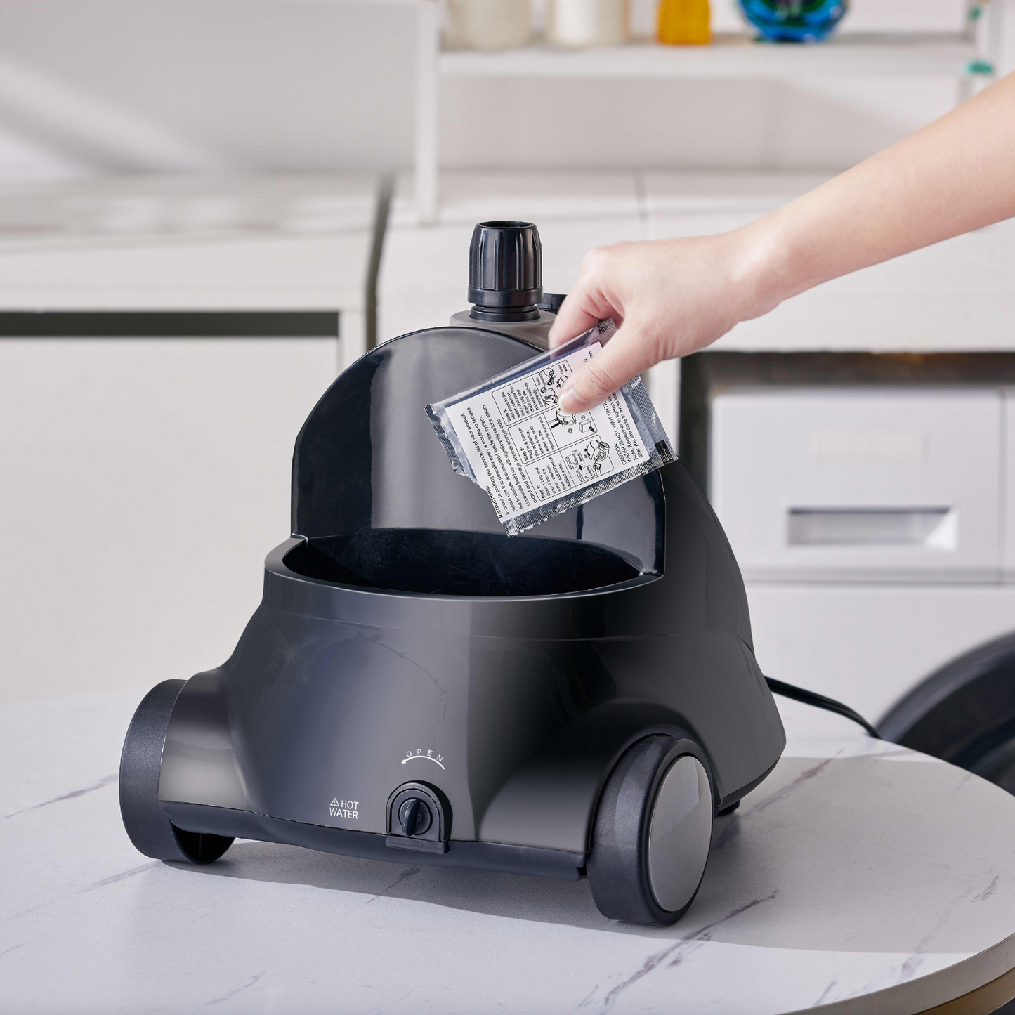 a pack of decalcifier being poured in to the water reservoir of a black steamer for clothes