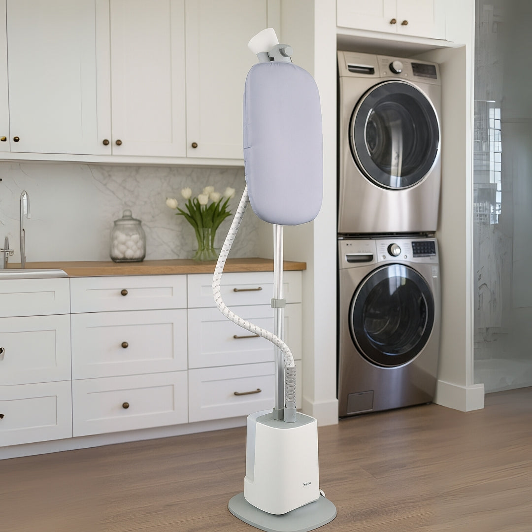 White garment steamer on a stand in a laundry room with washing machines.