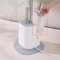 White handheld steamer with gray base on a beige surface