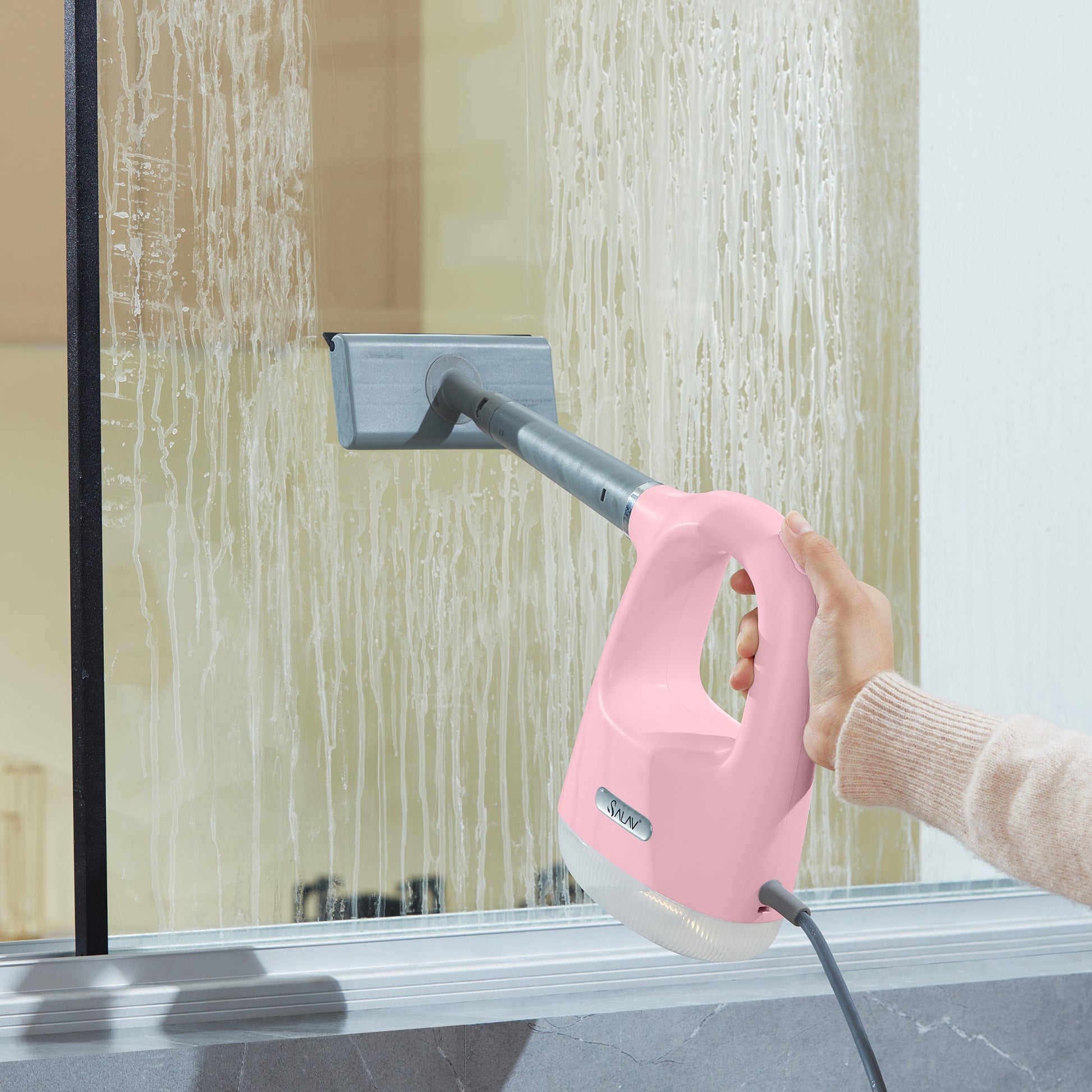 CS100PinkPerson cleaning a glass surface with a pink handheld steam cleaner with Squeegee Attachment