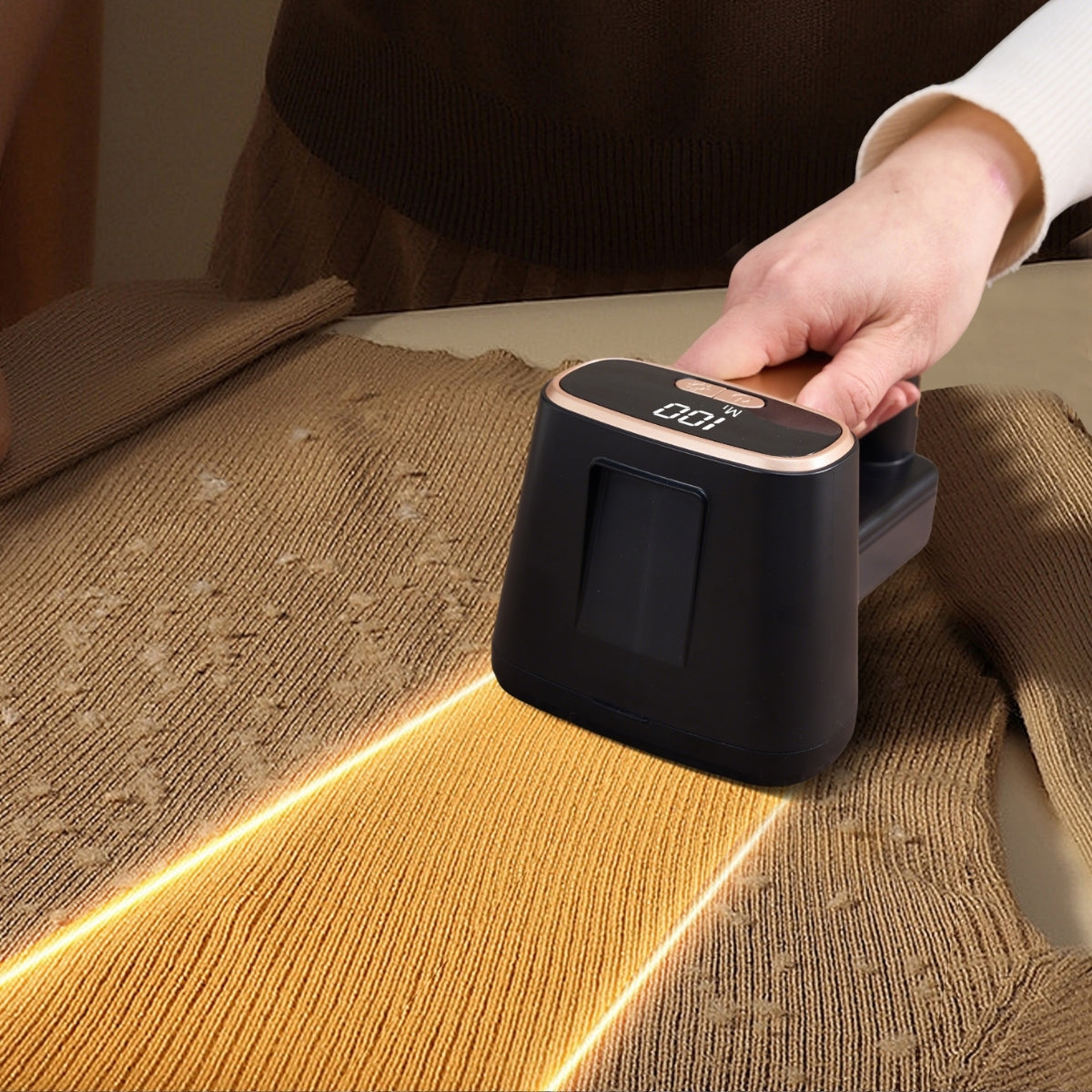 FS2 black and gold fabric shaver removing fuzz from a brown sweater