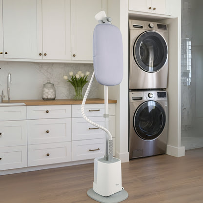 White garment steamer on a stand in a laundry room with washing machines.