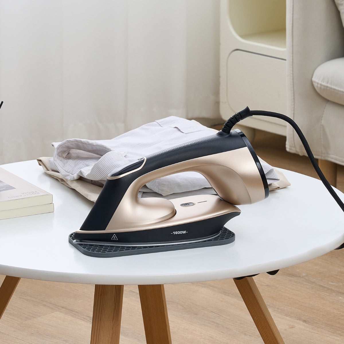 IS1600 Iron resting on silicone pad on a table next to pile of clothes