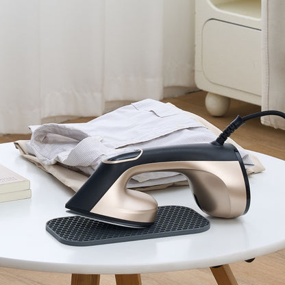 Steam iron on a white table with clothes in the background