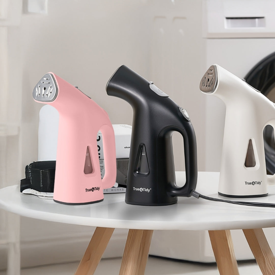 TS38 + Pink + Three handheld steamers in pink, black, and white on a white table.